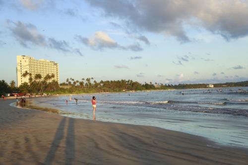 a person standing on a beach with people in the water at Single Fin Weligama in Weligama