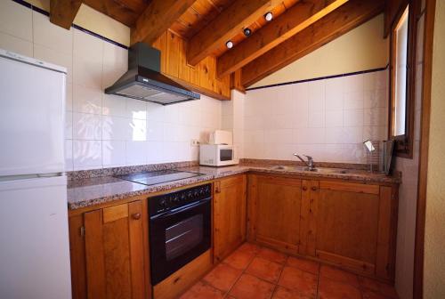 a kitchen with wooden cabinets and a stove top oven at El carrero in Abella