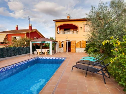 a villa with a swimming pool and a house at Belvilla by OYO Casa Las Palmeras in El Vendrell