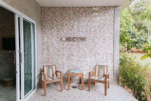 two chairs and a table in front of a brick wall at DG House in Thongsala