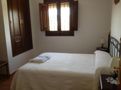 a bedroom with a bed with white sheets and a window at Casa Rural La Loma in Iznájar