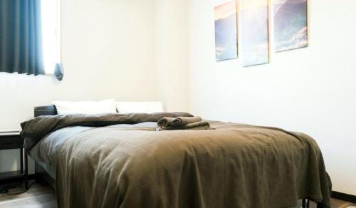 a bedroom with a bed with a blanket on it at Sun Hotel in Tokyo