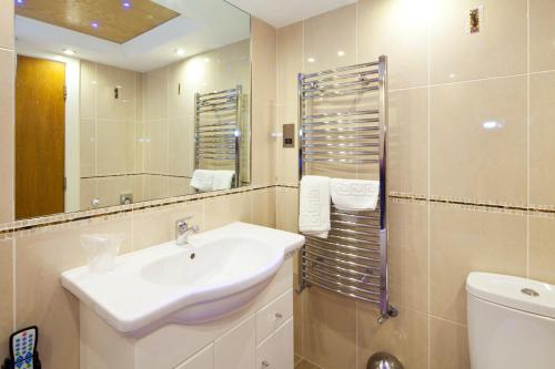 a bathroom with a sink and a toilet and a mirror at Queens Mansions: Queens Suite in Blackpool