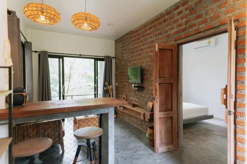 a room with a brick wall and a bar with stools at DG House in Thongsala