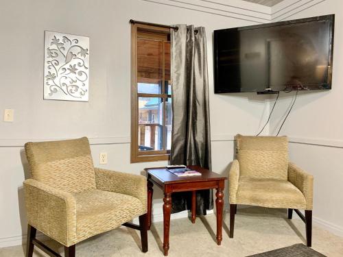 a living room with two chairs and a table and a television at Spring Creek Hotel in Hot Springs