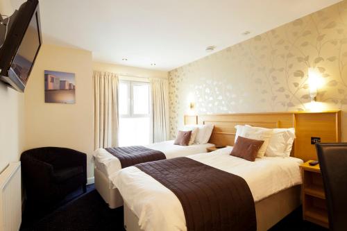 a hotel room with two beds and a television at Queens Mansions: Princess Suite in Blackpool