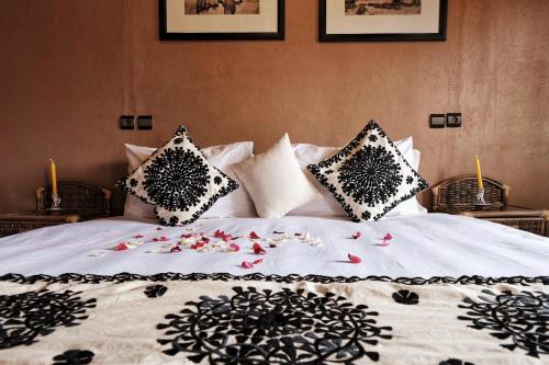 a bed with pillows and flowers on it at Riad Ouarzazate in Ouarzazate