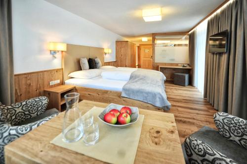 a hotel room with a bed and a bowl of fruit on a table at Hotel Maria Theresia in Ischgl