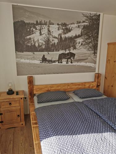 a bedroom with a wooden bed with a picture on the wall at Penzion Loučka Bystřice in Bystrzyca