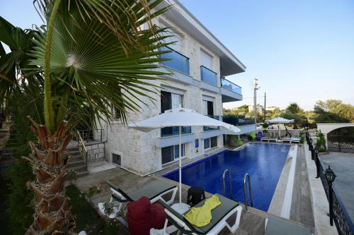a hotel with a swimming pool with chairs and an umbrella at Villa Noble in Demre