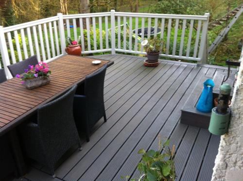 a wooden deck with a table and some plants at Ma demeure in Le Gué-de-Longroi