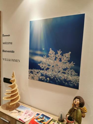 a painting on a wall with a christmas tree on a table at Fiocco di Neve in Tarvisio