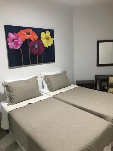 a bed with two pillows and a painting of flowers at Apartamento na Praia da Barra in Rio de Janeiro
