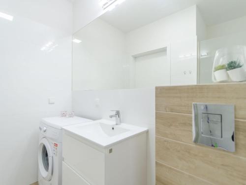 a white bathroom with a washing machine and a sink at Feniks Apartament in Kołobrzeg