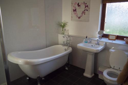 a bathroom with a tub and a toilet and a sink at Highland Croft B&B in Onich