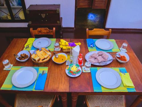 een houten tafel met borden en eten erop bij Thalpe Walawwa Heritage Villa With Private Beach Access in Unawatuna