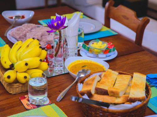 een tafel met bananen en brood en een fruitmand bij Thalpe Walawwa Heritage Villa With Private Beach Access in Unawatuna