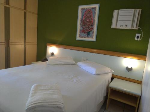 a bedroom with a white bed with a green wall at Apart Hotel Quartier Latin in Vitória