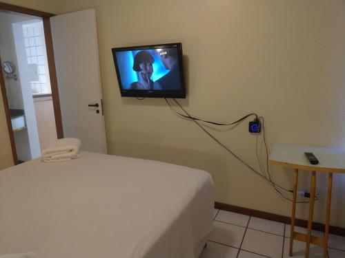 a bedroom with a bed and a tv on the wall at Apart Hotel Quartier Latin in Vitória