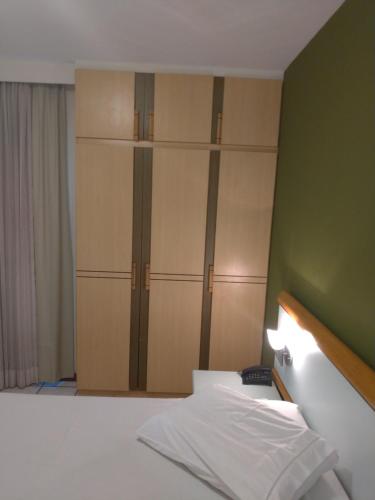 a bedroom with wooden cupboards and a white bed at Apart Hotel Quartier Latin in Vitória