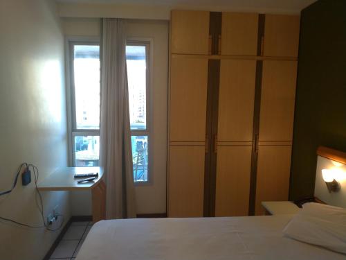a bedroom with a white bed and a window at Apart Hotel Quartier Latin in Vitória
