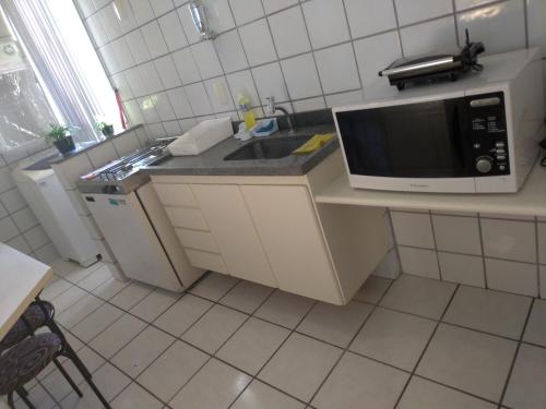 a kitchen with a sink and a microwave at Apart Hotel Quartier Latin in Vitória