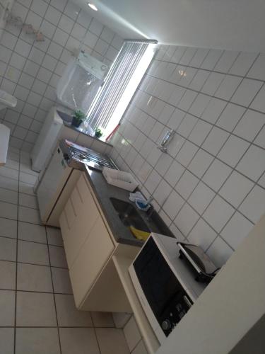 a small white kitchen with a sink and a window at Apart Hotel Quartier Latin in Vitória