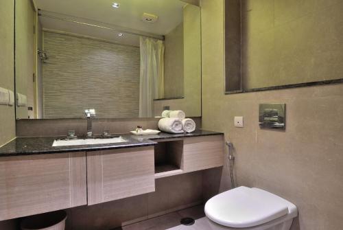 uma casa de banho com um WC, um lavatório e um espelho. em Hotel Royal Grand - Opposite Axis Bank East Patel Nagar em Nova Deli