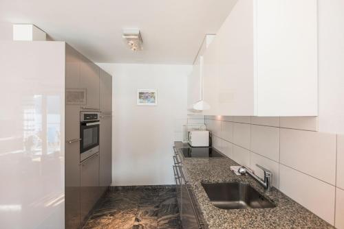a kitchen with white cabinets and a sink at Alpenblick - Direct lake view in Brienz