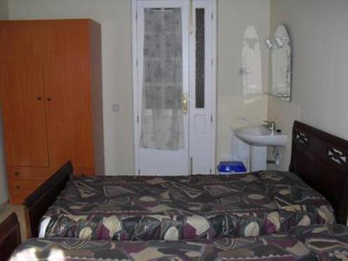 1 dormitorio con 1 cama y lavamanos. en Hostal del Mar, en Madrid