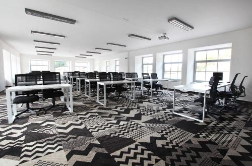 a large room with tables and chairs on a geometric carpet at Cett in Náměšť nad Oslavou
