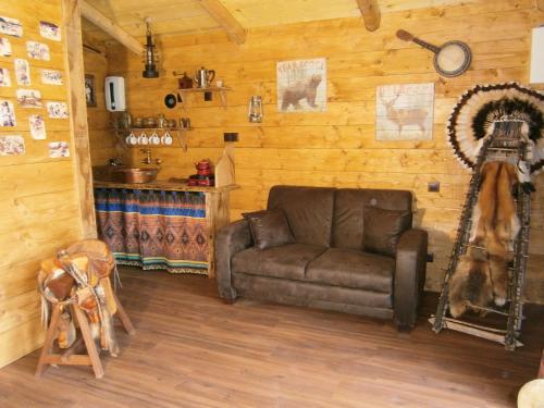 a living room with a couch in a room with wooden walls at Chambre d'hôte atypique "trappeur" West little ranch in Guiscriff