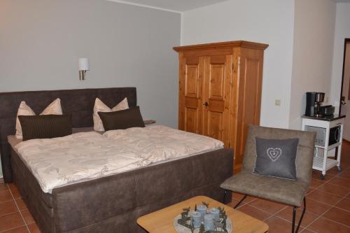 a bedroom with a bed and a chair and a table at Hoffmann's Apartment in der Residenz Bocksbergblick in Hahnenklee-Bockswiese