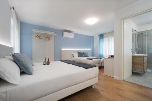 a bedroom with a large white bed and a bathroom at ZONA 30 Bike Guesthouse in Palmanova