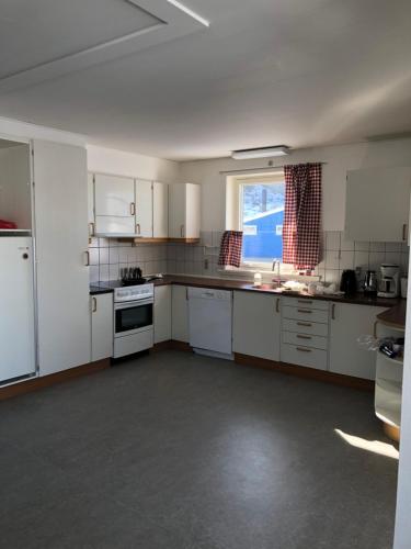 a large kitchen with white cabinets and a window at isi4u hostel, dogsled, snowmobiling in Sisimiut
