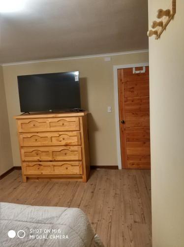 a bedroom with a flat screen tv on a dresser at Hospedaje Puerto Varas in Puerto Varas