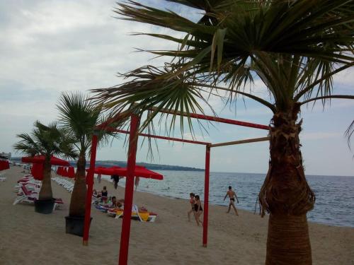 people on the beach with palm trees and umbrellas at Villa Sky Music in Obzor