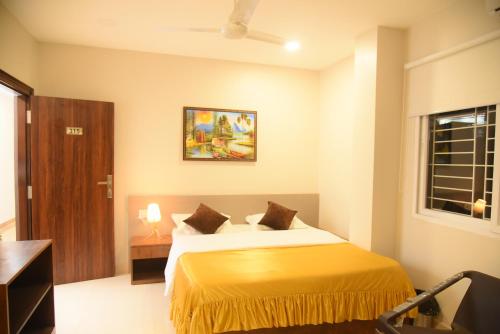 a bedroom with a bed with a yellow bedspread at Hotel Tea City in Dibrugarh