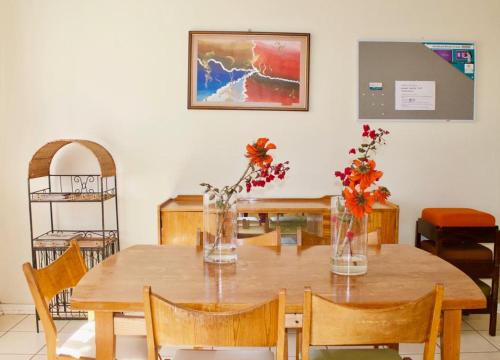 a dining room table with vases of flowers on it at Emfuleni Country House in Butterworth