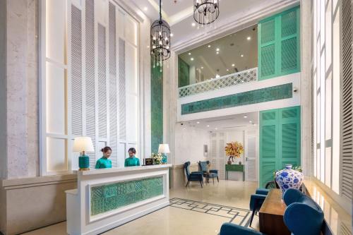 un vestíbulo con dos personas sentadas en un salón en Minasi HanoiOi Hotel en Hanoi