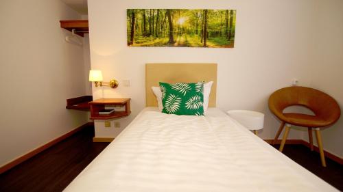 a bedroom with a bed with a green pillow on it at gut-Hotel Tannenhof in Haiger