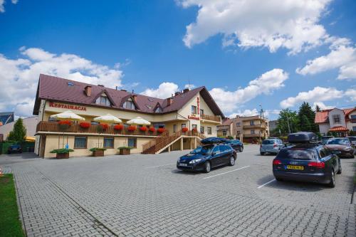 a parking lot with cars parked in front of a building at Hotel Kantoria in Tarnów