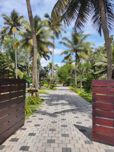 a brick road with palm trees in the distance at Maliekal Heritance Cherai Beach Cochin in Cherai Beach