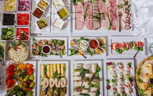 a display of different types of food in white trays at Hotel Kantoria in Tarnów