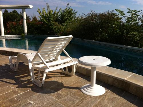 a white rocking chair and a table next to a swimming pool at Villa Sky Music in Obzor