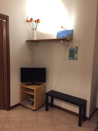 um quarto com uma televisão, uma mesa e uma prateleira em Costa Verde Apartment em Predore