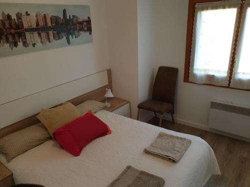 ein Schlafzimmer mit einem Bett mit einem roten Kissen darauf in der Unterkunft Apartamento Montes blancos in Jaca