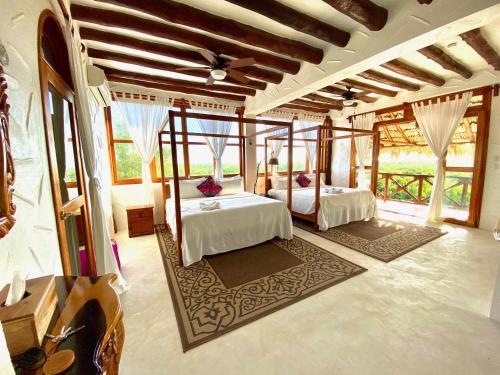 a bedroom with two beds in a room with windows at Palapas del Sol in Holbox Island