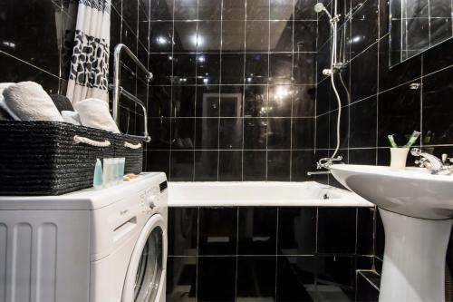 a black tiled bathroom with a washing machine and a sink at 2х-кімнатна квартира на Майдані Незалежності in Kyiv