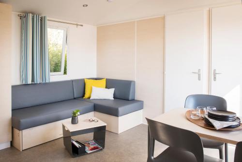 un salon avec un canapé bleu et une table dans l'établissement Résidence de vacances Villa Cottage, à Bréhémont